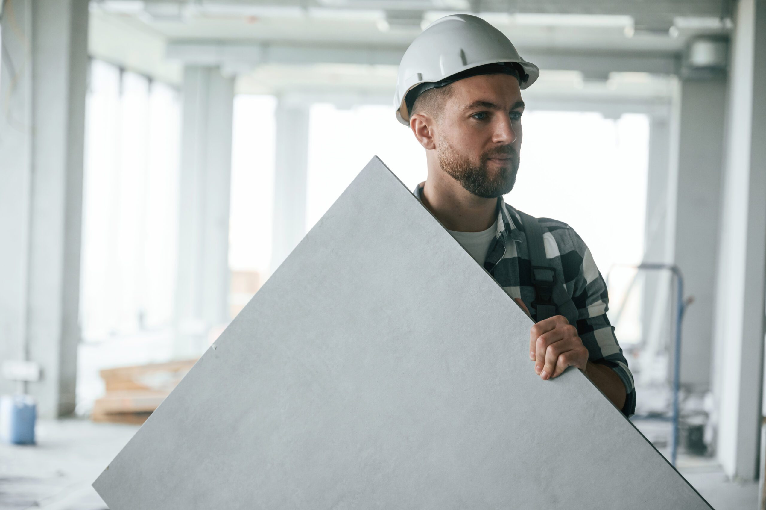 Drywall and Ceilings 9 Construction worker in uniform in empty unfinished room.