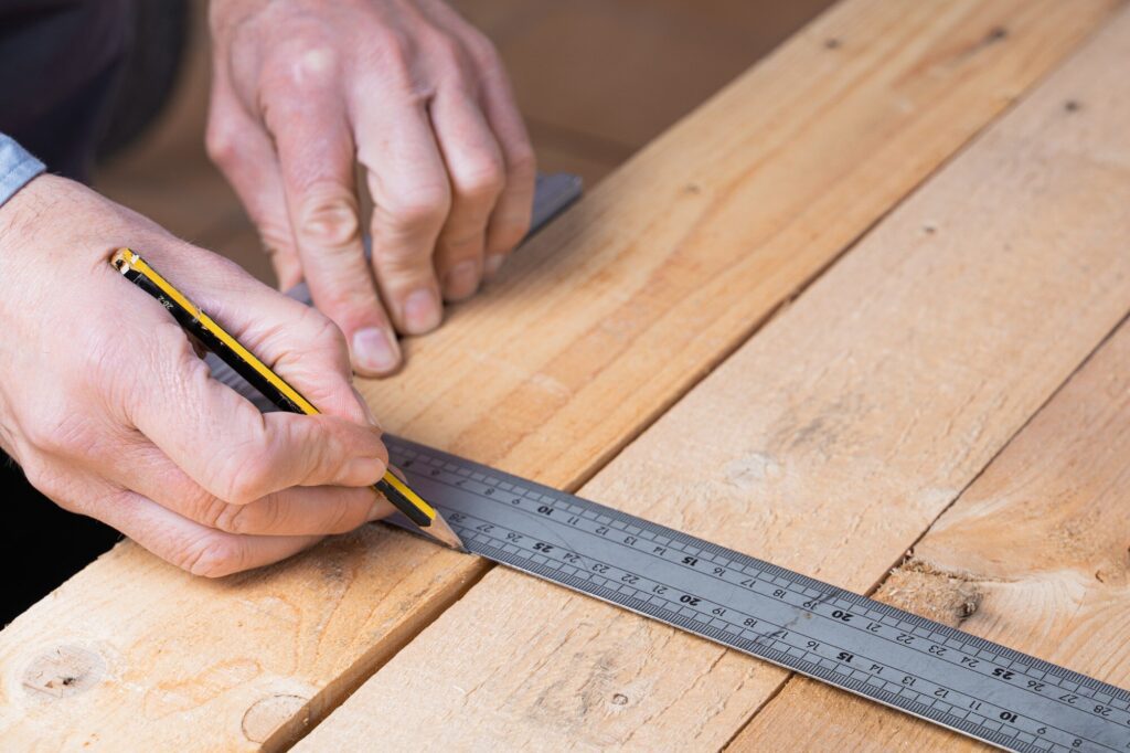 Carpentry 5 Carpenter measuring wooden desk in a safe work environment