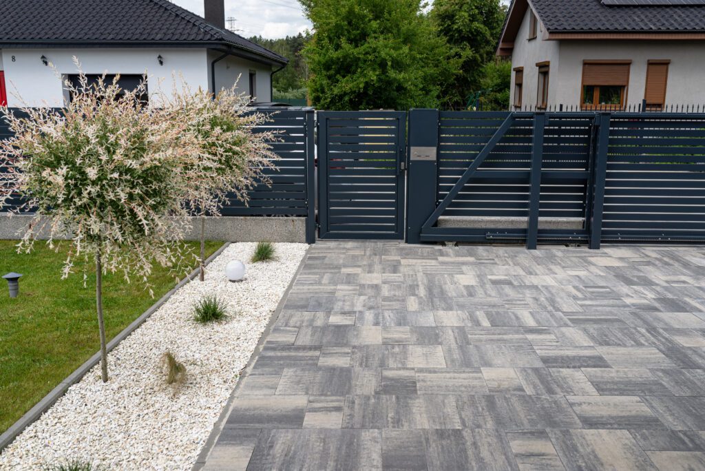 Block Paving And Patio 1 A modern panel fence in anthracite color, a visible sliding gate to the garage and a wicket with a letterbox.