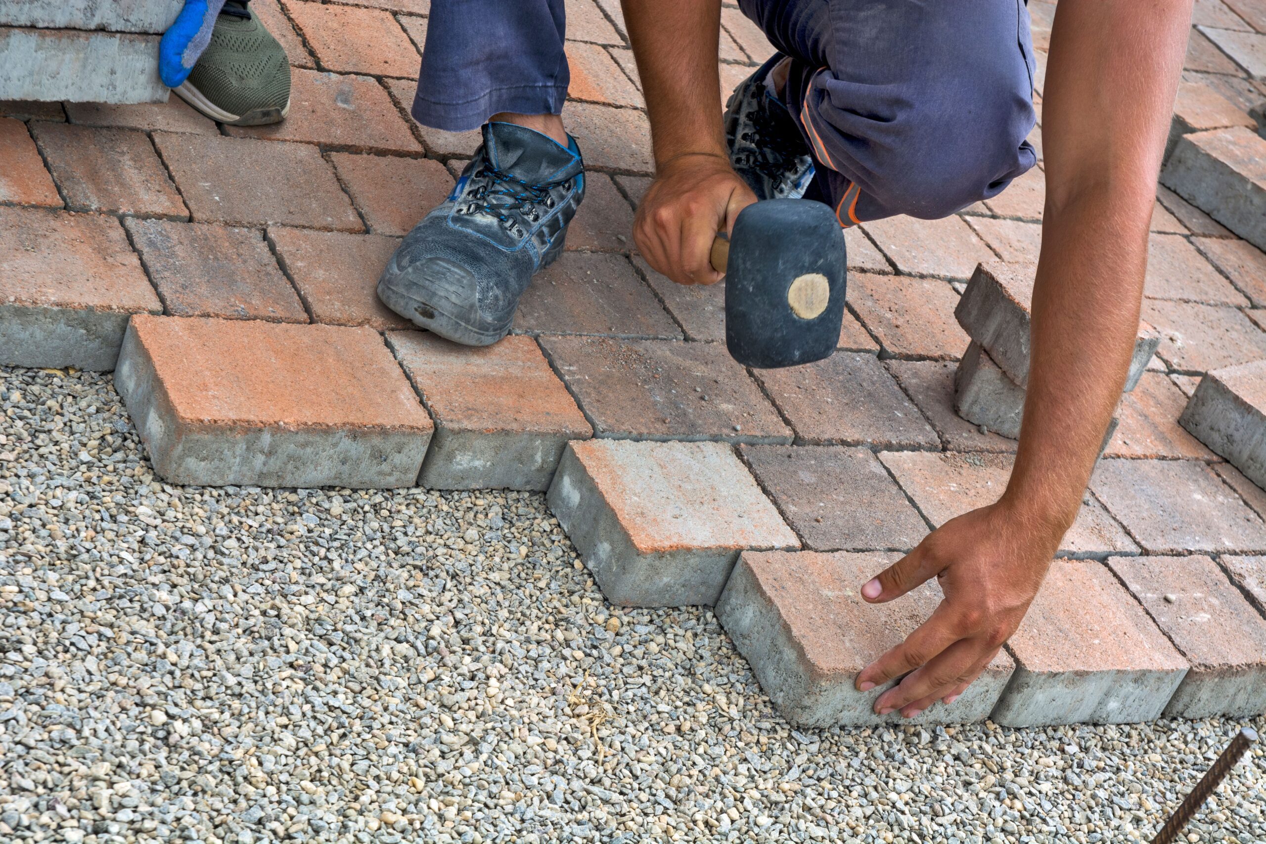 Block Paving And Patio 4 A construction worker repairing a brick wall in an outdoor area