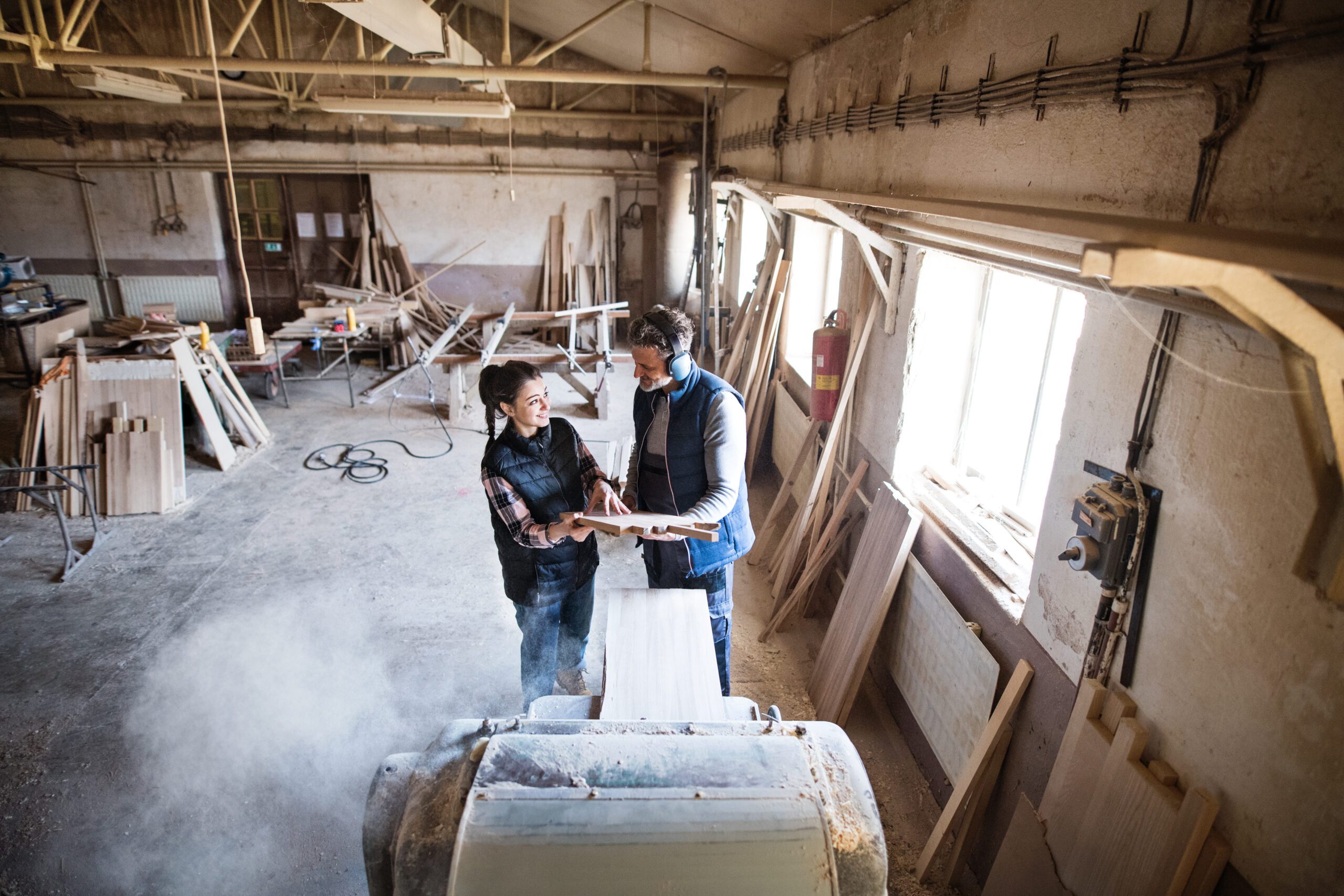 Interior Renovations 4 Portrait of a man and woman workers in the carpentry workshop, holding a piece of wood.
