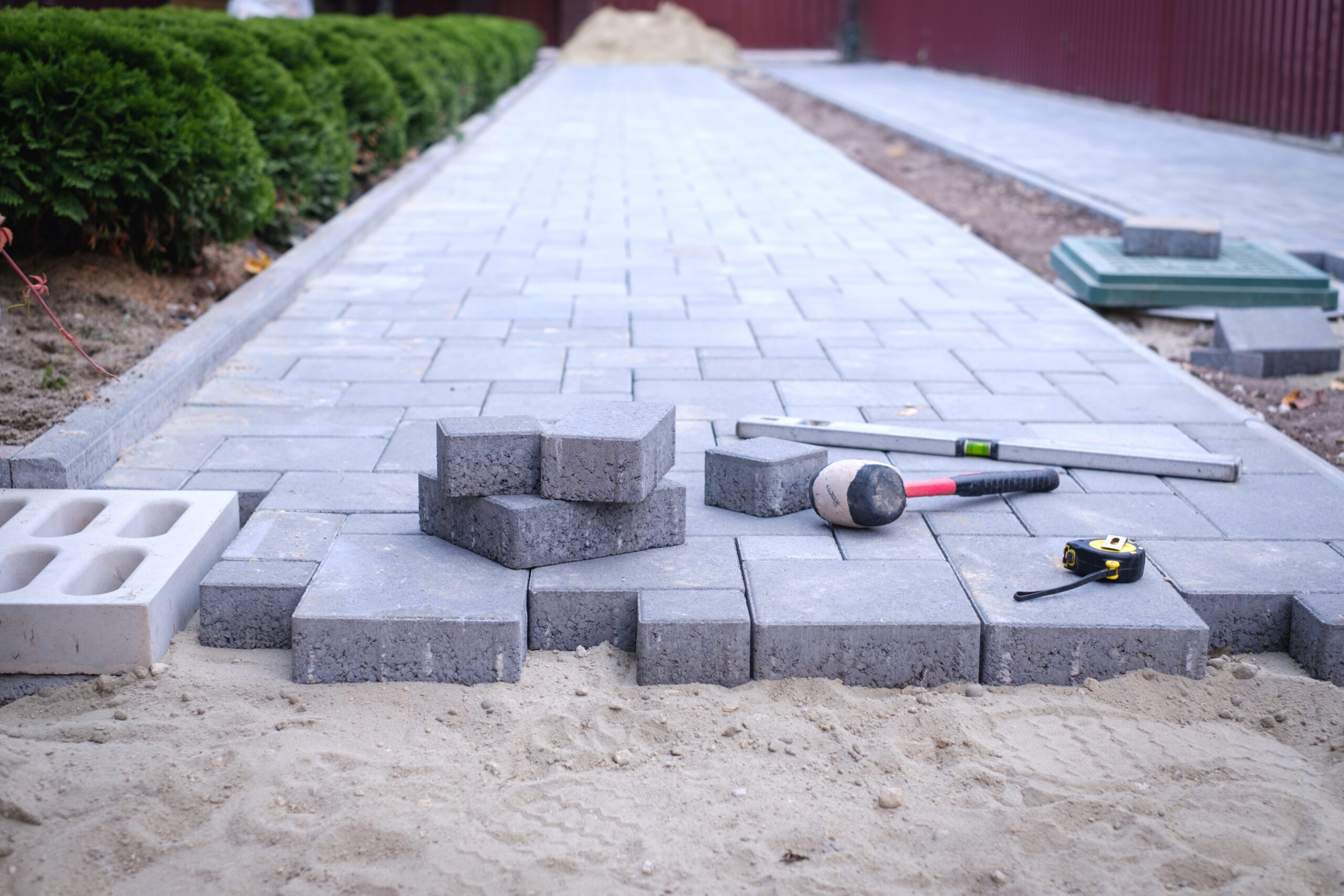Block Paving And Patio 9 Paving stones pathway paving background. Installing tools on foreground