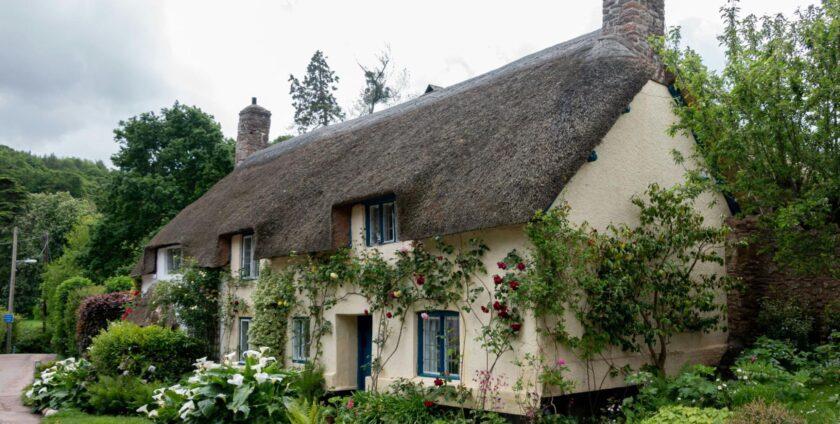 A cottage with white walls and a lot of flowers in the garden