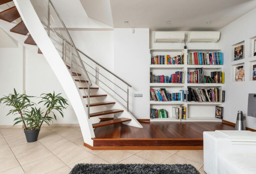 10 Simple and Effective Under Stairs Storage Ideas 2 A bright interior with a staircase and a bookcase.