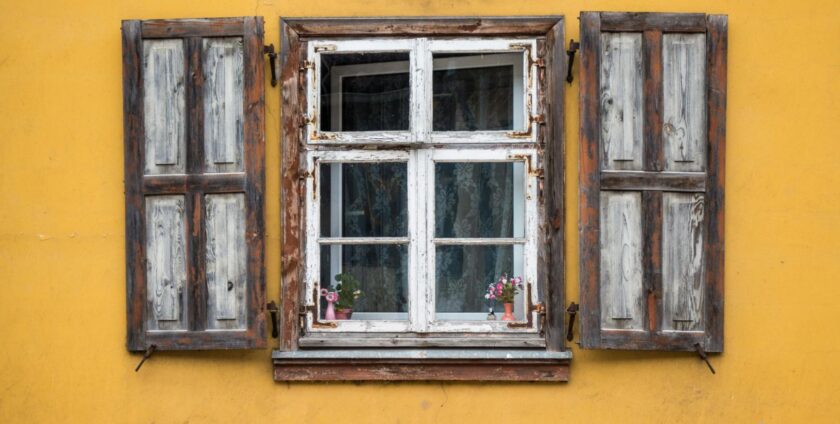 old window with shutters on a yellow wall
