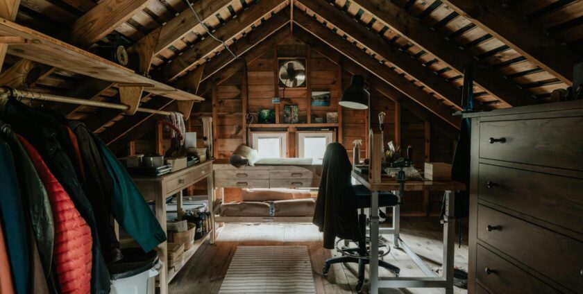 Attic office space with old clothes and a table visible