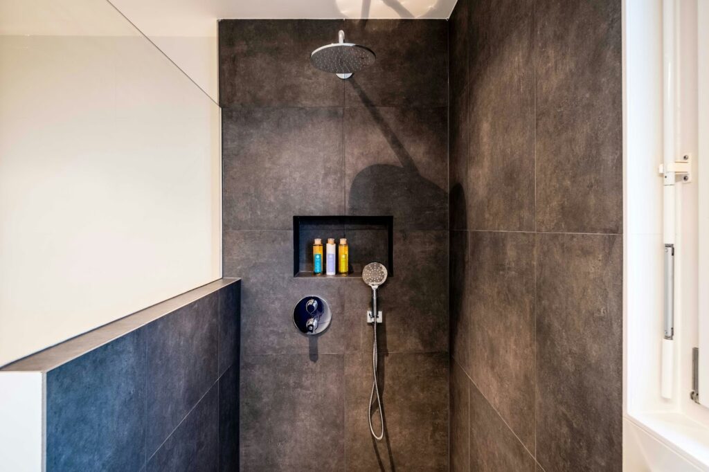Bathroom shower with tiles and cosmetics visible